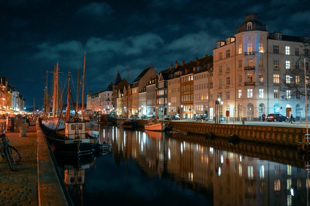 Copenhagen Nyhavn canal at night with lit buildings and sailing boat reflections in the water — UK to Denmark removals to Copenhagen by Trunk Logistics