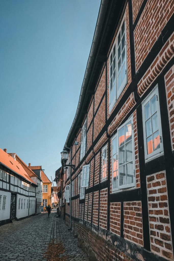 Cobbled street in a Danish provincial town with traditional half-timbered red brick buildings — UK to Denmark removals to Jutland and regional Danish addresses by Trunk Logistics