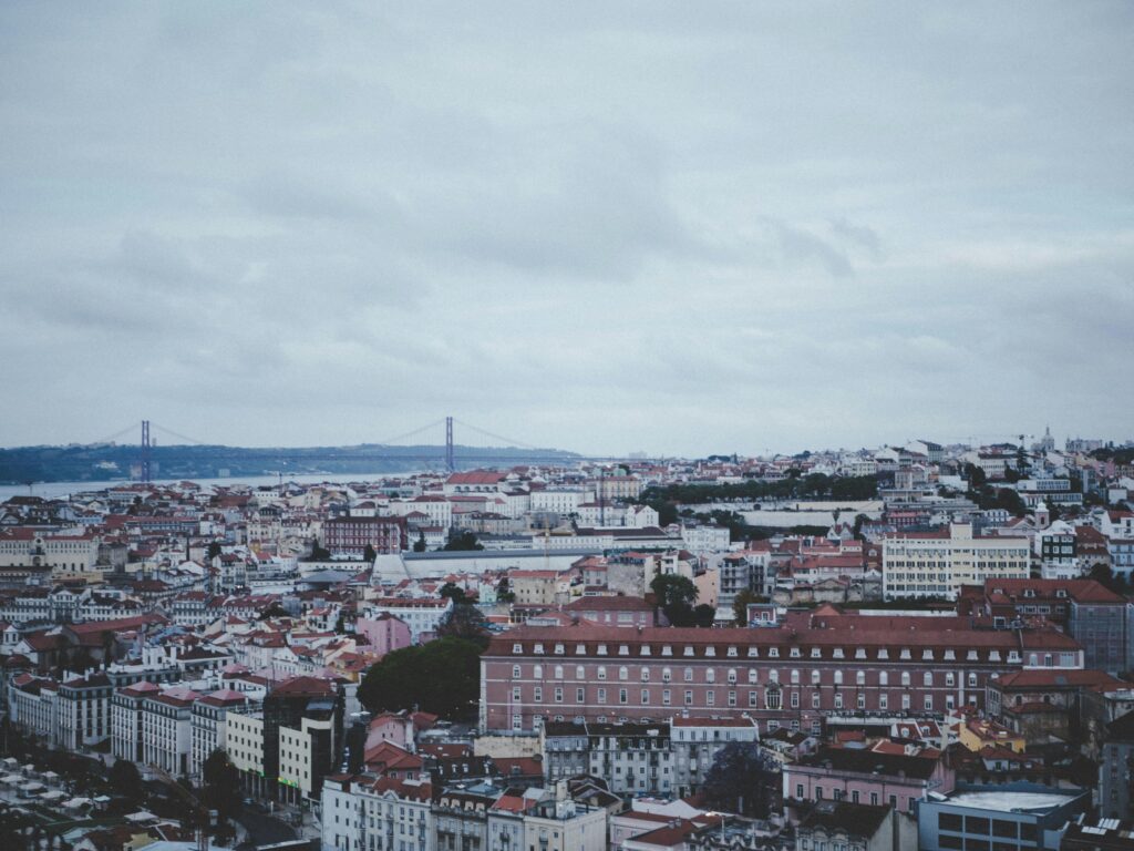 Aerial view of Lisbon cityscape with the 25 de Abril Bridge spanning the Tagus river and the Cristo Rei statue visible on the far bank — UK to Portugal removals to Lisbon by Trunk Logistics