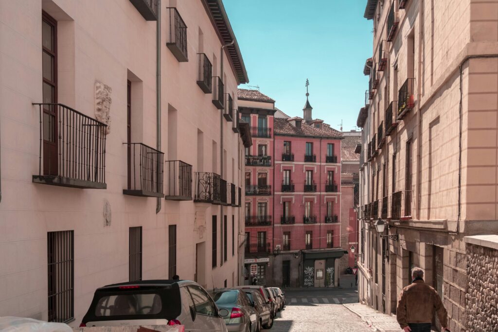 Narrow cobbled street in Madrid old town with ornate pink building and wrought iron balconies — UK to Spain removals to Madrid by Trunk Logistics