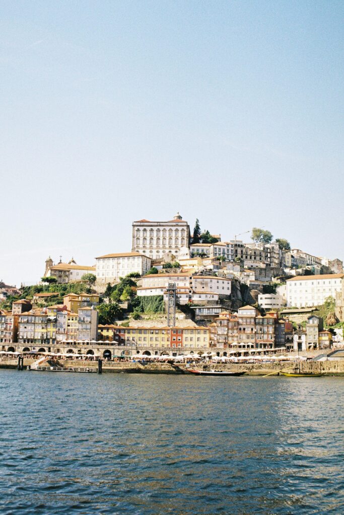 Porto Ribeira waterfront viewed from the Douro river showing coloured buildings climbing the hillside with the Episcopal Palace at the top — UK to Portugal removals to Porto by Trunk Logistics