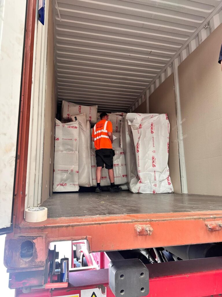 Trunk Logistics crew member loading export-wrapped furniture into a shipping container at Essex depot for UK to USA international removal