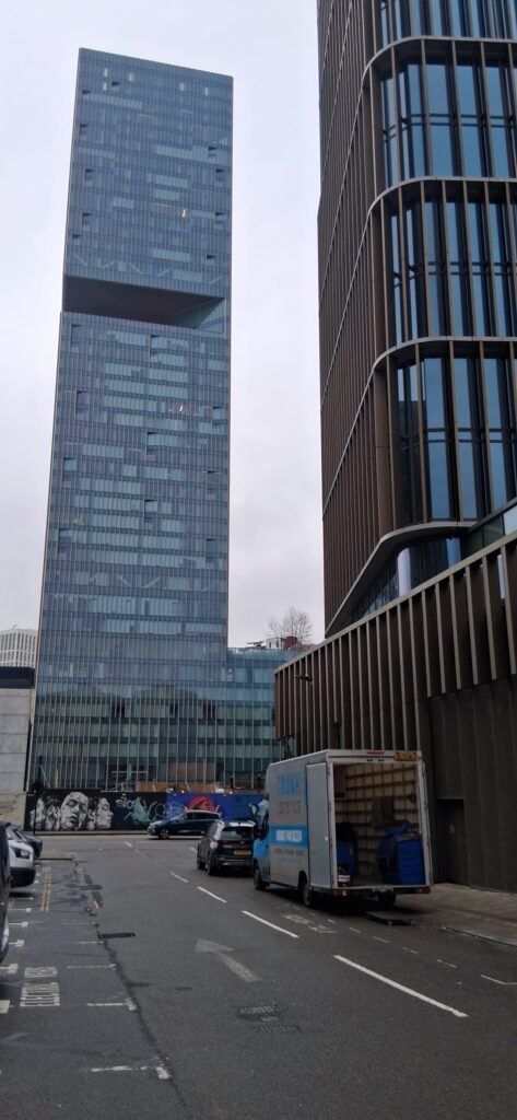 Trunk Logistics removals van loading household items outside a high-rise apartment building in London