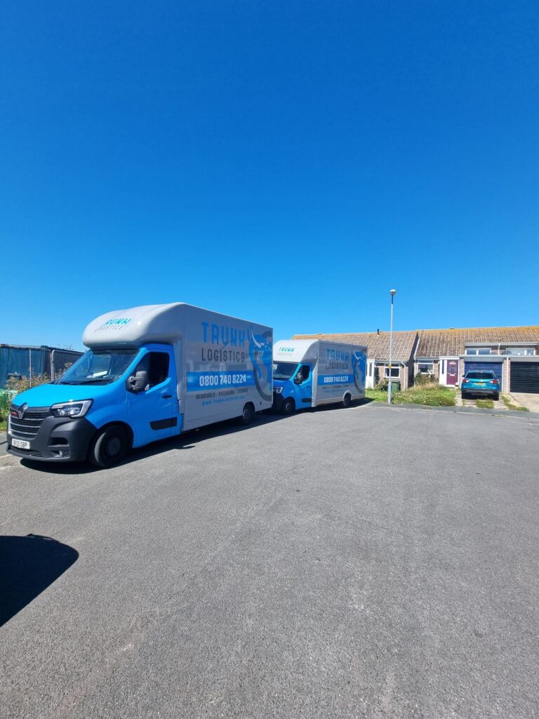 Two Trunk Logistics branded removal vehicles parked outside a residential property on a sunny day — home removals service planned from survey to delivery