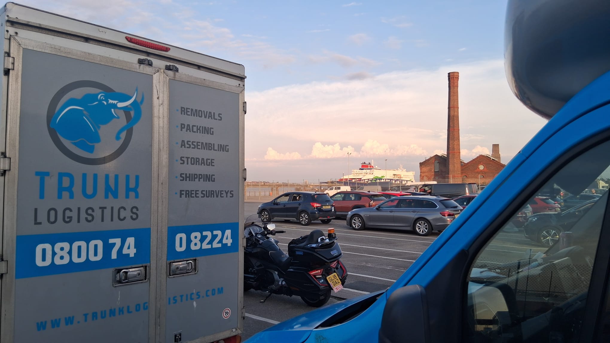 UK to Ireland Removals Trunk Logistics removal van at Liverpool ferry port with the Ireland-bound ferry vessel docked in the background — UK to Ireland removals via Liverpool